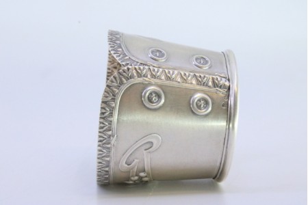 Argola de guardanapo em prata em forma de punho rebordado e relevada com motivos florais.